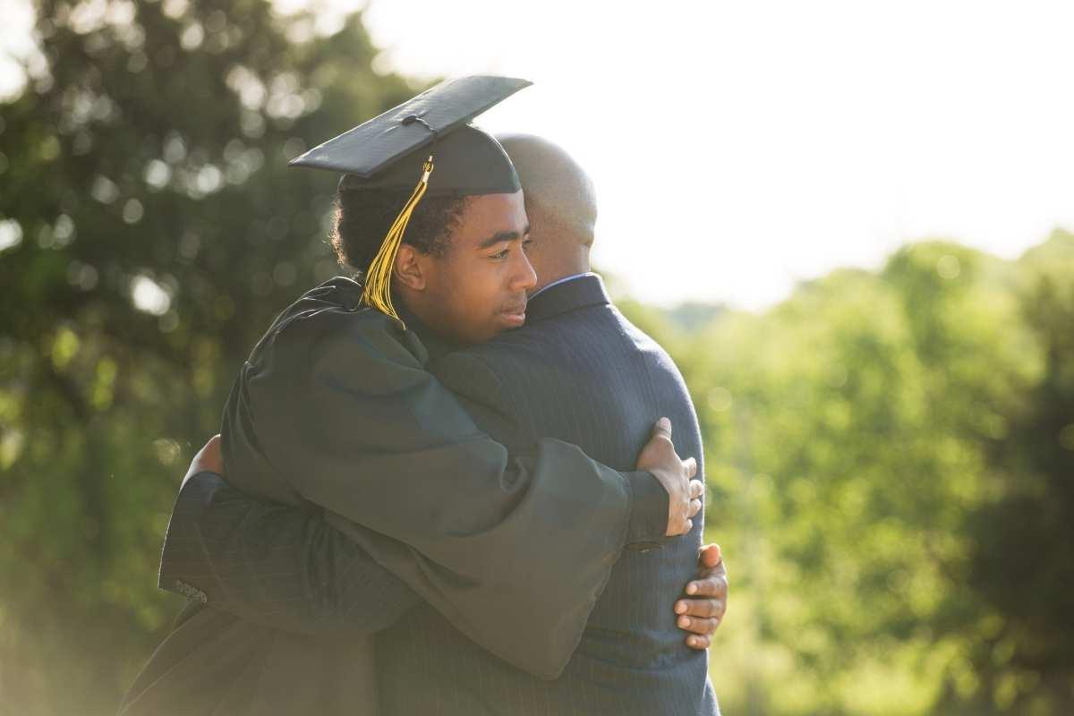graduate in cap and gown hugging person